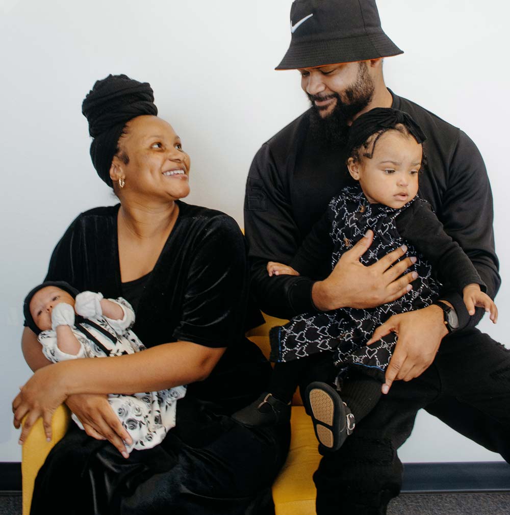 Ujima Scholarship Arkansas Doula. Image of happy family with new baby and toddler.